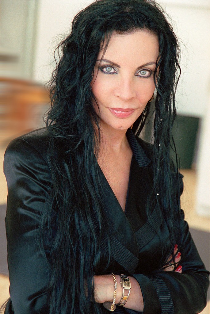 Woman with long dark hair wearing a silky black short smiling at the camera.